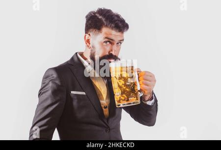 Porträt eines hübschen bärtigen Mannes, der ein Craft-Bier probiert. Stilvoller, hübscher Mann in schwarzem Anzug, der Bier trinkt. Schwule trinken Bier. Stockfoto