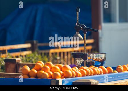 Nahaufnahme eines manuellen Entsafters aus Metall und einer Menge frischer Orangen auf dem Ladentisch Stockfoto