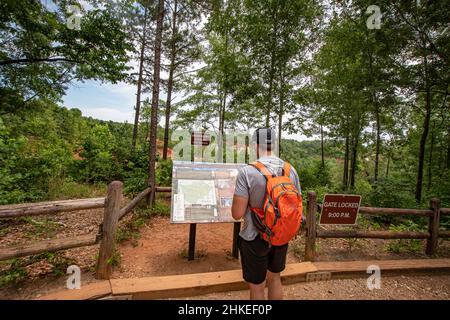 Lumpkin, Georgia, USA - 6. Juni 2021: Ein männlicher Wanderer untersucht die Wanderkarte im Providence Canyon State Park im Südwesten von Georgia. Stockfoto