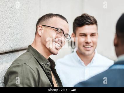 Freunde im Geschäft. Aufnahme von drei jungen Geschäftsleuten, die vor städtischem Hintergrund eine Diskussion führen. Stockfoto