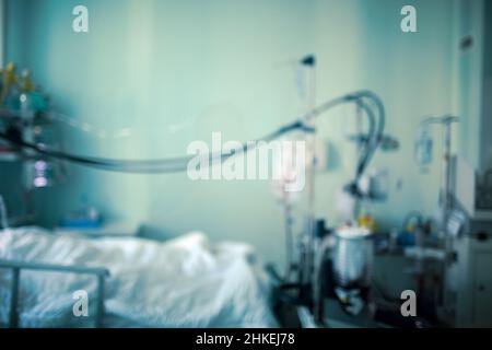 Silhouette eines Patienten auf einer kleinen Station auf der Intensivstation, verbunden mit Lebenserhaltungsanlagen, unfokussierter Hintergrund. Stockfoto