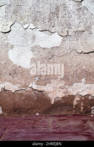 Verwitterte verputzte Wand mit tiefen Rissen als alter Texturhintergrund. Stockfoto