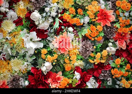 Foto für Hintergrundmaterial der bunten Wand mit vielen künstlichen Blumen geschmückt Stockfoto