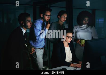 Versammeln Sie sich um alle. Eine Kurzaufnahme einer vielfältigen Gruppe von Geschäftsleuten, die sich in ihrem Büro um einen einzigen Computer versammelten. Stockfoto