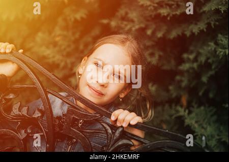 Portrait nachdenklich seriöse ehrliche acht Jahre alte Mädchen Gesicht späht aus abstrakten Metallformen in der Natur. Vorpubertär Alter der Kinder und ihre Stockfoto