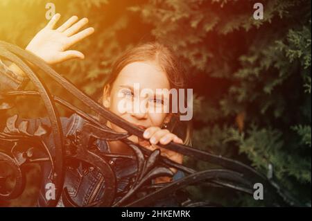 Portrait nachdenklich seriöse ehrliche acht Jahre alte Mädchen Gesicht späht aus abstrakten Metallformen in der Natur. Vorpubertär Alter der Kinder und ihre Stockfoto