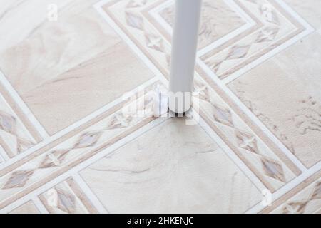 Gerissenes Linoleum. Stuhlbein und zerrissenes Linoleum. Loch im Linoleum. Stuhl auf dem Boden. Die Spuren der Verwendung der Bodenbeläge. Verschleißfestigkeit. Schutz agai Stockfoto