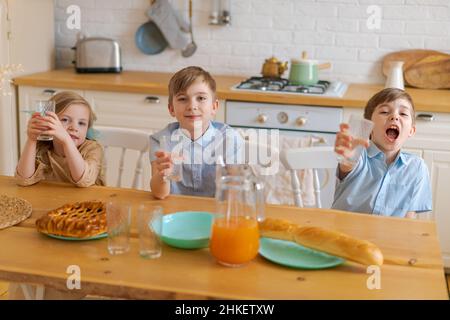 Kaukasische Mutter sitzt am Tisch in der Küche Kinder Vater serviert Lebensmittel für sie selektive Fokus. Morgen für meine Tochter und zwei Söhne, Konzept Beziehung zwischen Kindern und Eltern Stockfoto