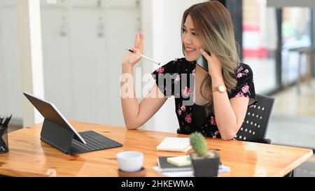 Attraktive Frau mit niedlichem Lächeln reden, mit Gespräch auf dem Handy, während Remote-Arbeit und Ruhe im Café. Stockfoto