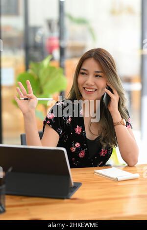 Porträt, schöne asiatische Frau im Gespräch mit jemandem auf ihrem Handy, während Blick in die Ferne mit einem Lächeln. Stockfoto