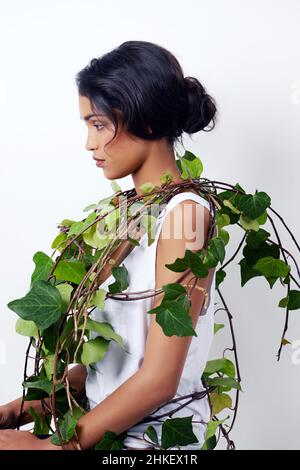 Ivy Beauty. Studioaufnahme einer attraktiven jungen ethnischen Frau mit Laub über der Schulter. Stockfoto