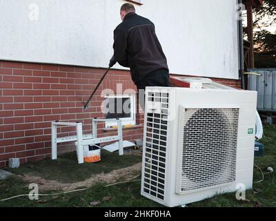 Der Installierer installiert die Wärmepumpe in einem Einfamilienhaus Stockfoto