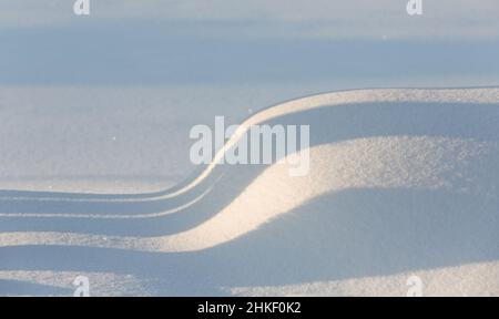 Einige leichte Schatten auf Schneeverwehung an einem sonnigen Tag Stockfoto