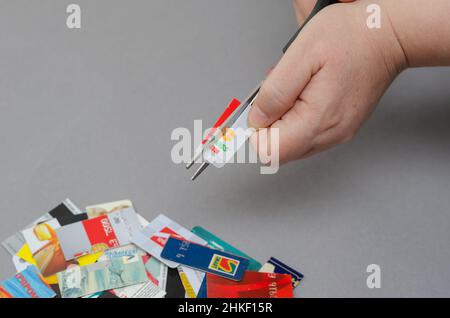 Nahaufnahme von Frauenhänden, die Bankkarten zerstören. Eine Erwachsene Frau verwendet eine Schere, um Kreditkarten von verschiedenen Banken zu schneiden. Selektiver Fokus. Kiew, Ukrain Stockfoto