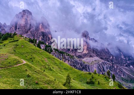 Blick auf die Sella-Gruppe mit dem Gipfel des SAS dla Luesa links und dem Murfeit-Turm rechts, bedeckt von dunklen Gewitterwolken, vom Grödner Pass aus gesehen. Stockfoto