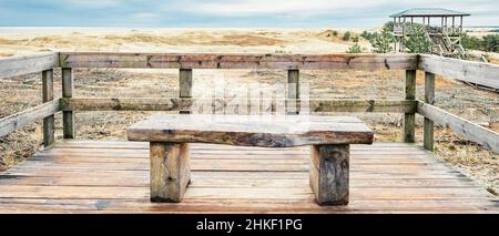 Eine Holzbank mit Blick auf die Sanddünen der Kurischen Lagune und der Kurischen Bucht Stockfoto