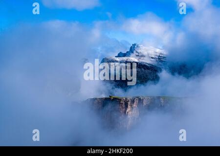 Frischer Schnee auf dem Gipfel des Piz Boe und die von Wolken bedeckten Felswände der Sella-Gruppe, vom Gipfel des Grand Cirs aus gesehen. Stockfoto