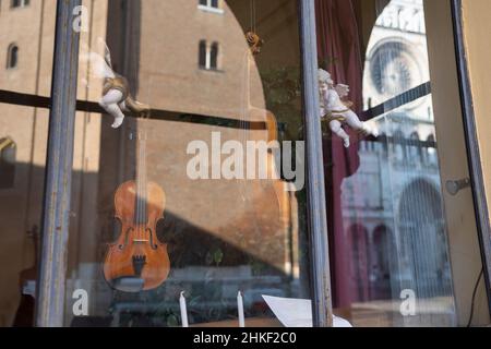 Schaufenster eines Geigenbauers: Handgefertigte Violinen im Schaufenster und Spiegelung der Kathedrale von Cremona, Italien. Stockfoto