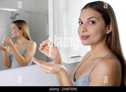 Hautpflegeprogramm. Schöne Frau, die die Kamera mit einer Pipette in der Hand mit Serum-feuchtigkeitsspendenden Anti-Aging-Antioxidans betrachtet. Stockfoto