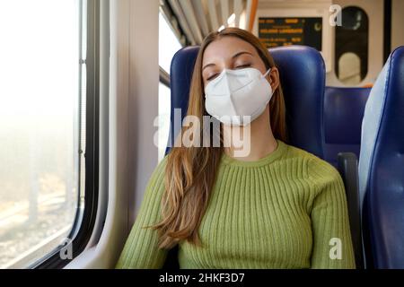 Sie können ruhig schlafen. Entspannte schöne Frau mit medizinischer Gesichtsmaske schlafen im Zug sitzen. Zug Passagier sicher reisen sitzen in einem Stockfoto