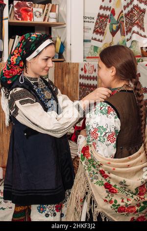 Zwei Mädchen in traditionellen ukrainischen Kleidern und bestickten Hemden bereiten sich auf die Aufführung vor Stockfoto