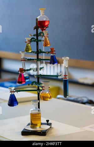 Chemielabor der Schule. Verschiedene farbige Lösungen in Kolben mit Tafel im Hintergrund. Stockfoto