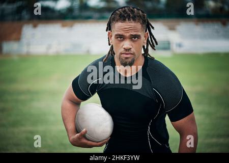 Ich bin bereit, ein paar Punkte zu sammeln. Ein Porträt eines hübschen jungen Rugby-Spielers, der einen Rugby-Ball hält, während er auf dem Spielfeld steht. Stockfoto