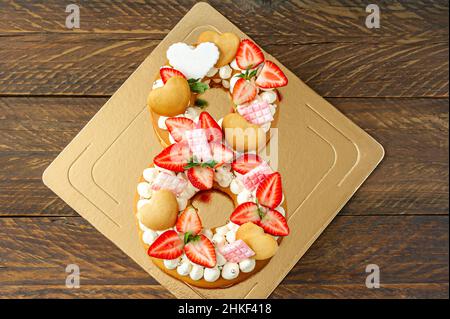 Biskuitkuchen mit Erdbeeren, rosafarbenen Milchschokoladenstäben, Silberstreuseln, Vanillecreme und herzkranken Keksen in Form der Nummer 8. Spring sweet de Stockfoto