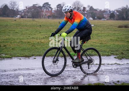 WIMBLEDON LONDON, GROSSBRITANNIEN. 4th. Februar 2022. Ein Mann, der auf dem Wimbledon Common, im Südwesten Londons, im kalten, eiskalten Regen radelt, als das Met-Büro heute Abend einen Rückgang der Temperaturen und des Schnees für den Südwesten Englands prognostiziert hat. Quelle: amer ghazzal/Alamy Live News Stockfoto