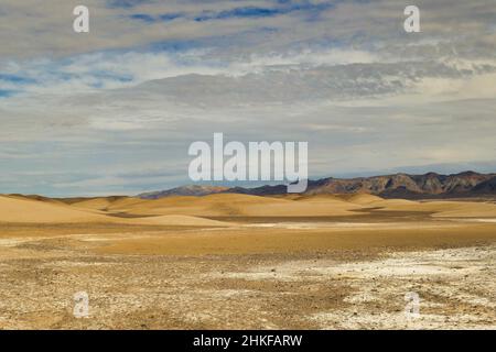 Abstrakte Landschaft aus Dünen und dunklen Bergen in der Wüste und Salzebenen zwischen Tecopa und der China Ranch Date Farm, Kalifornien, Mojave-Wüste Stockfoto