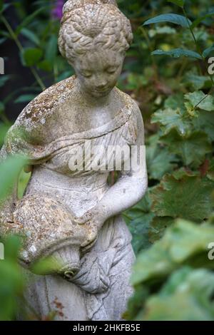 Loozen, Niederlande - Aug 17 2021 Eine Gartenstatue einer Frau, die Wasser aus einem Krug in den Ada Hofmans Pond Gardens gießt Stockfoto