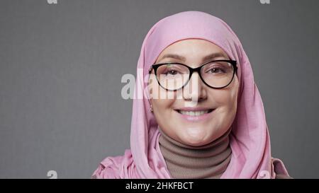 Junge Frau in Brille und Hijab lächelt in die Kamera schauen Stockfoto