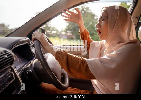 Frustrierte junge muslimische Frau, während sie ihr Auto fuhr Stockfoto