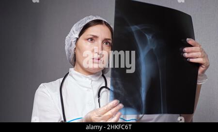 Die orthopädische Dame schaut sich das Röntgenbild im Klinikbüro an Stockfoto