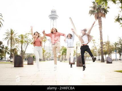 Multirassische Freunde springen vor Freude und feiern Erfolge in der Urlaubsstadt. Menschen, die Spaß haben. Stockfoto