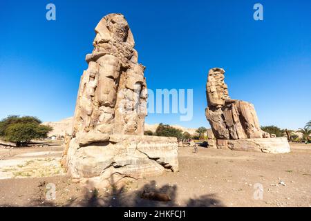 Luxor, Ägypten - 26. Januar 2022: Die Kolossi von Memnon in Luxor, Ägypten. Zwei massive Steinstatuen des Pharao Amenhotep III Stockfoto