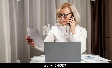 Blonde dame löst Arbeitsprobleme beim Telefonieren mit Gesten Stockfoto