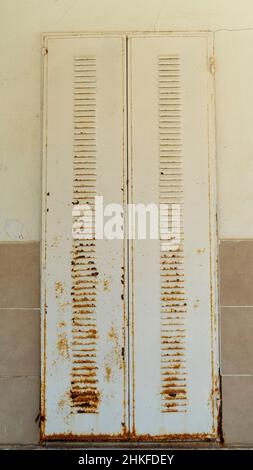 Verrostete Fensterläden aus Eisen. Verrostete Fensterläden der alten Haustüre. Rosty Shutter, der Umbau braucht. Jalousien mit beschädigten Lack. Bauunternehmen können verwenden Stockfoto