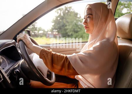 Schöne junge muslimische Frau, die ein Auto fährt Stockfoto