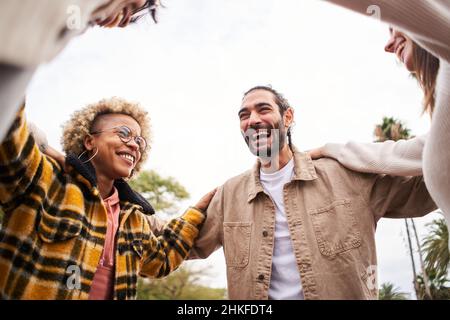 Porträt einer glücklichen multiethnischen Gruppe von Freunden, die sich umarmen und umarmen, lachen und Spaß im Freien haben Stockfoto