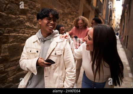 Gruppe von glücklichen Freunden, die im Freien telefonieren, während sie spazieren gehen und lachen. Stockfoto
