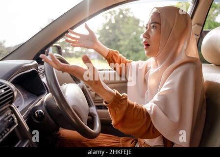 Frustrierte junge muslimische Frau, während sie ihr Auto fuhr Stockfoto