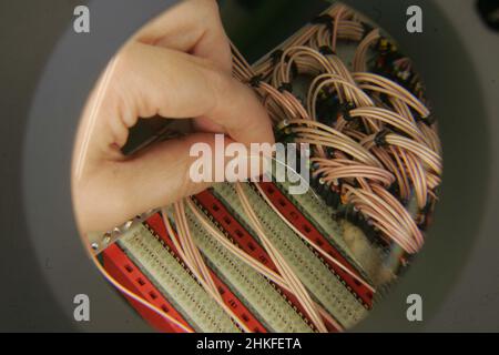 Techniker im Labor, der eine große beleuchtete Lupe verwendet, um elektrische Bauteile und Leiterplatten anzuzeigen. Stockfoto