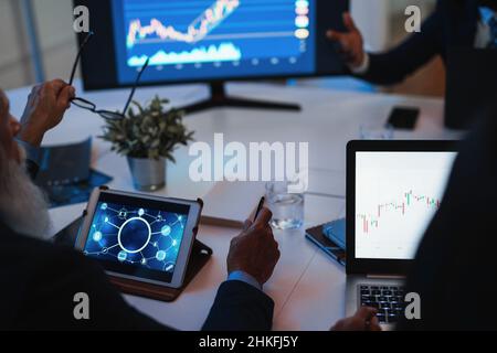 Trader-Team, das Aktienmarktanalysen innerhalb des Hedgefonds-Büros macht - Fokus auf dem rechten Computerbildschirm Stockfoto