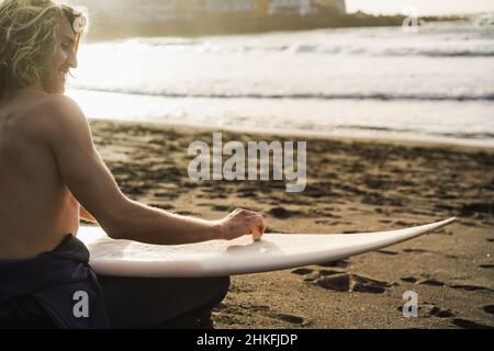 Junger Surfer-Mann, der sich auf die Surf-Session vorbereitet - Focus Wachs in der Hand Stockfoto