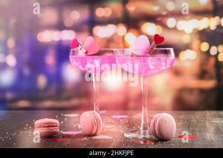 Zwei Gläser mit rosafarbenem Champagner, Makronen-Kekse an der Theke. Feier Valentinstag, Grußkarte. Speicherplatz kopieren Stockfoto