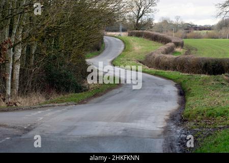 Eine kurvenreiche Landstraße im Winter, Warwickshire, England, Großbritannien Stockfoto
