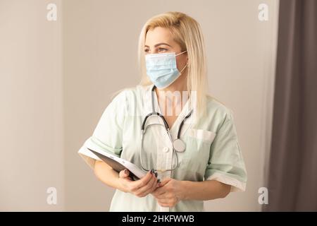 Ärztin, Die Scrubs Im Krankenhauskorridor Mit Einem Digitalen Tablet Trägt. Stockfoto