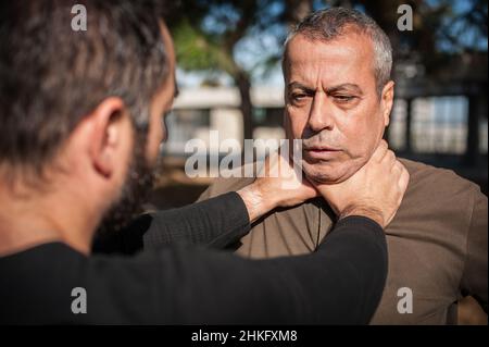 Zwei Männer streiten und kämpfen. Zwei Schläger kämpfen. Körperliche Konfrontation von Menschen draußen auf der Straße Stockfoto