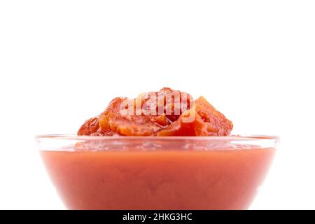 Gehackte Tomaten in Tomatensaft in Glasschüssel isoliert auf weißem Hintergrund Stockfoto